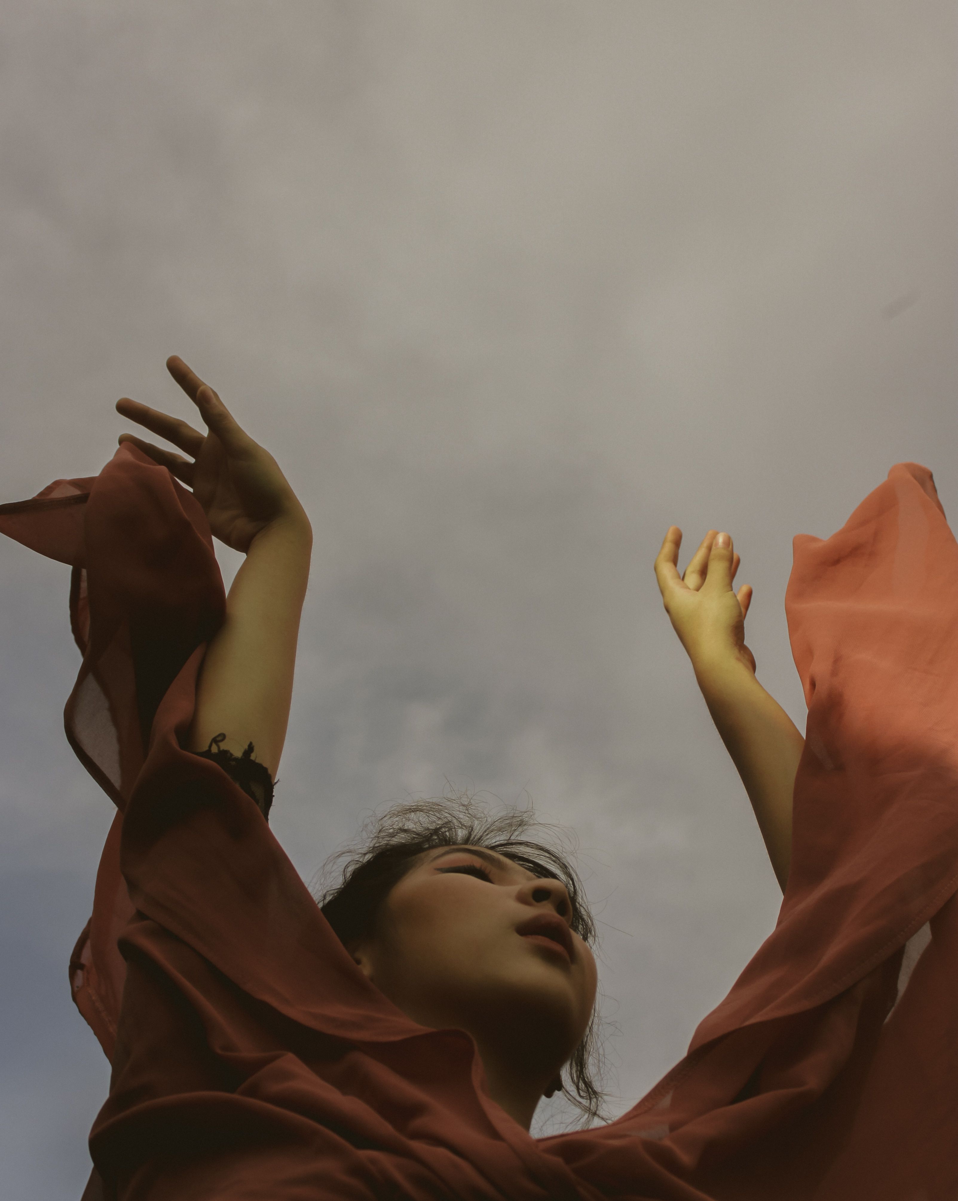 Low-Angle Shot of a Woman Raising Her Hands · Free Stock Photo