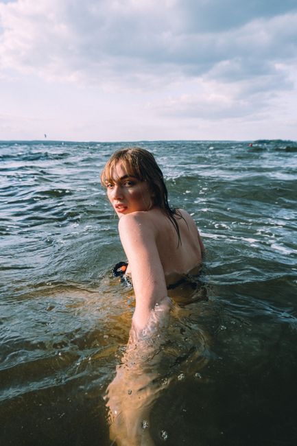 A woman swimming in open water under a cloudy sky, exuding freedom and adventure.
