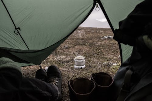 A Person Wearing Black Shoes Staying Inside the Tent