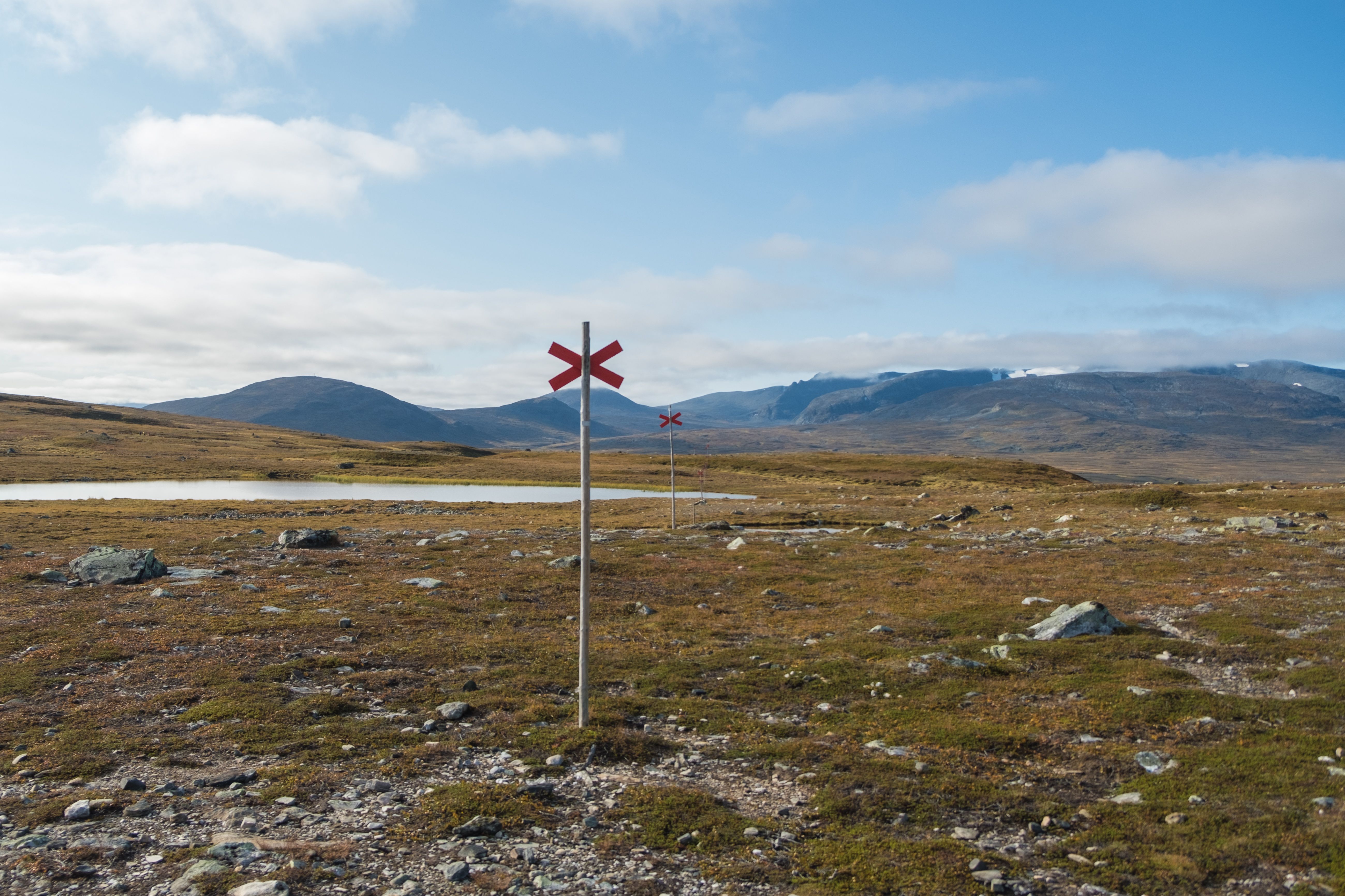 Explore the Jämtland hiking trail with scenic views and trail markers under a clear sky.