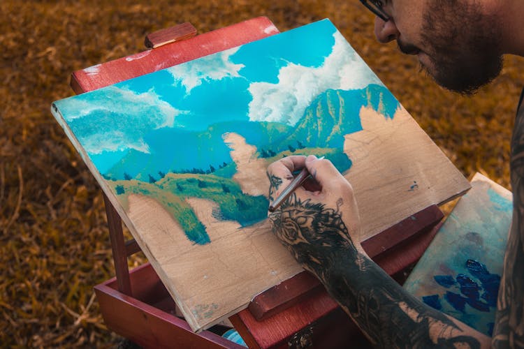 Tattooed Man Painting On A Board