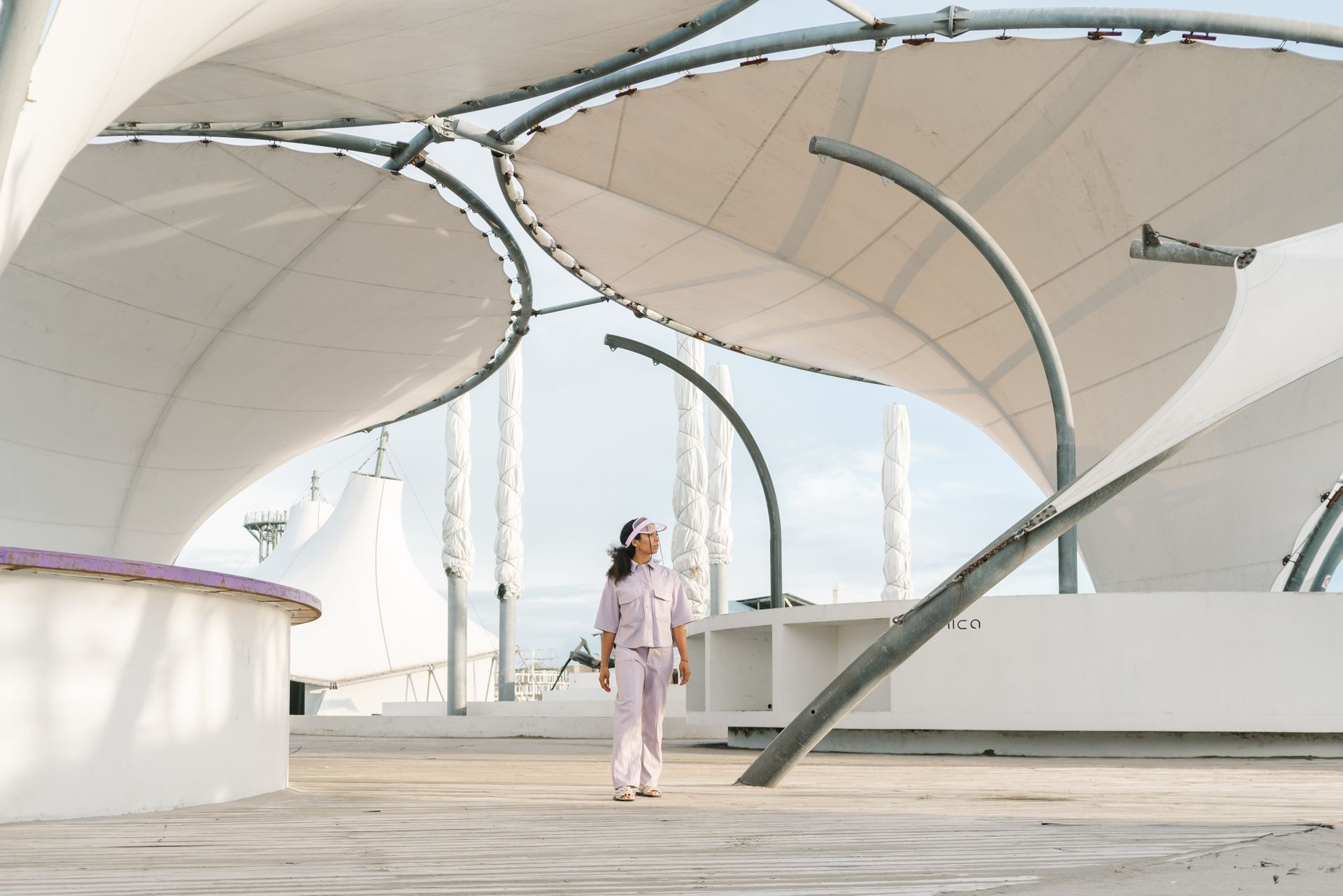 A woman walks under a contemporary architectural structure with curved steel designs.