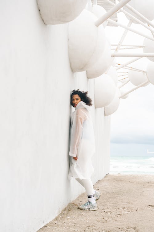 Brunette in Coat by Modern Building at Beach
