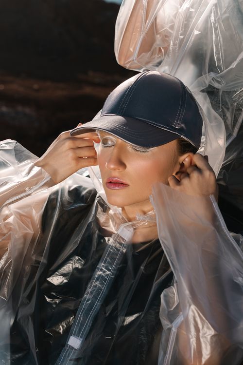 Free A woman with closed eyes in a stylish transparent raincoat, wearing a cap. Stock Photo