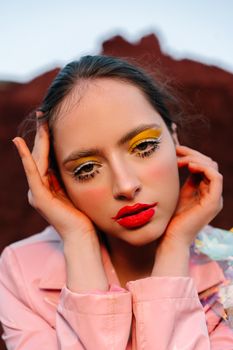 Close-up portrait of a woman with bold makeup and stylish fashion outdoors.
