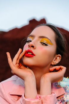 Artistic portrait of a woman showcasing bold makeup with red lips and yellow eyeshadow.