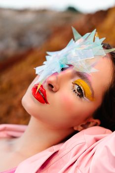 Vibrant portrait featuring avant-garde makeup and a unique cellophane accessory.