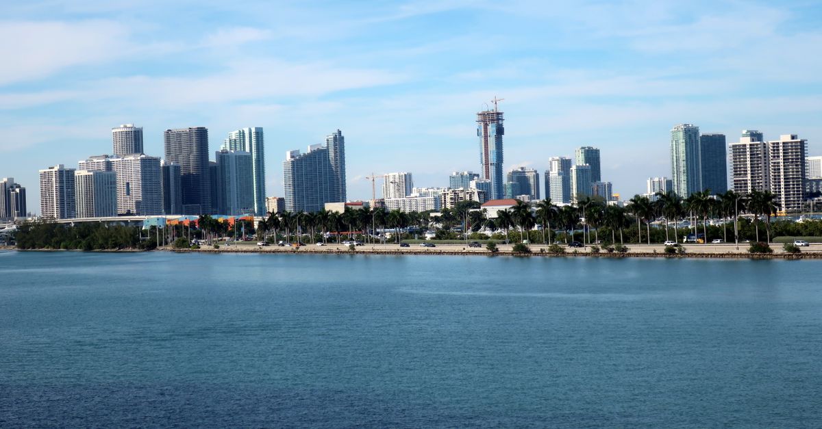 Miami Beach skyline featuring modern skyscrapers and a serene waterfront under a blue sky.