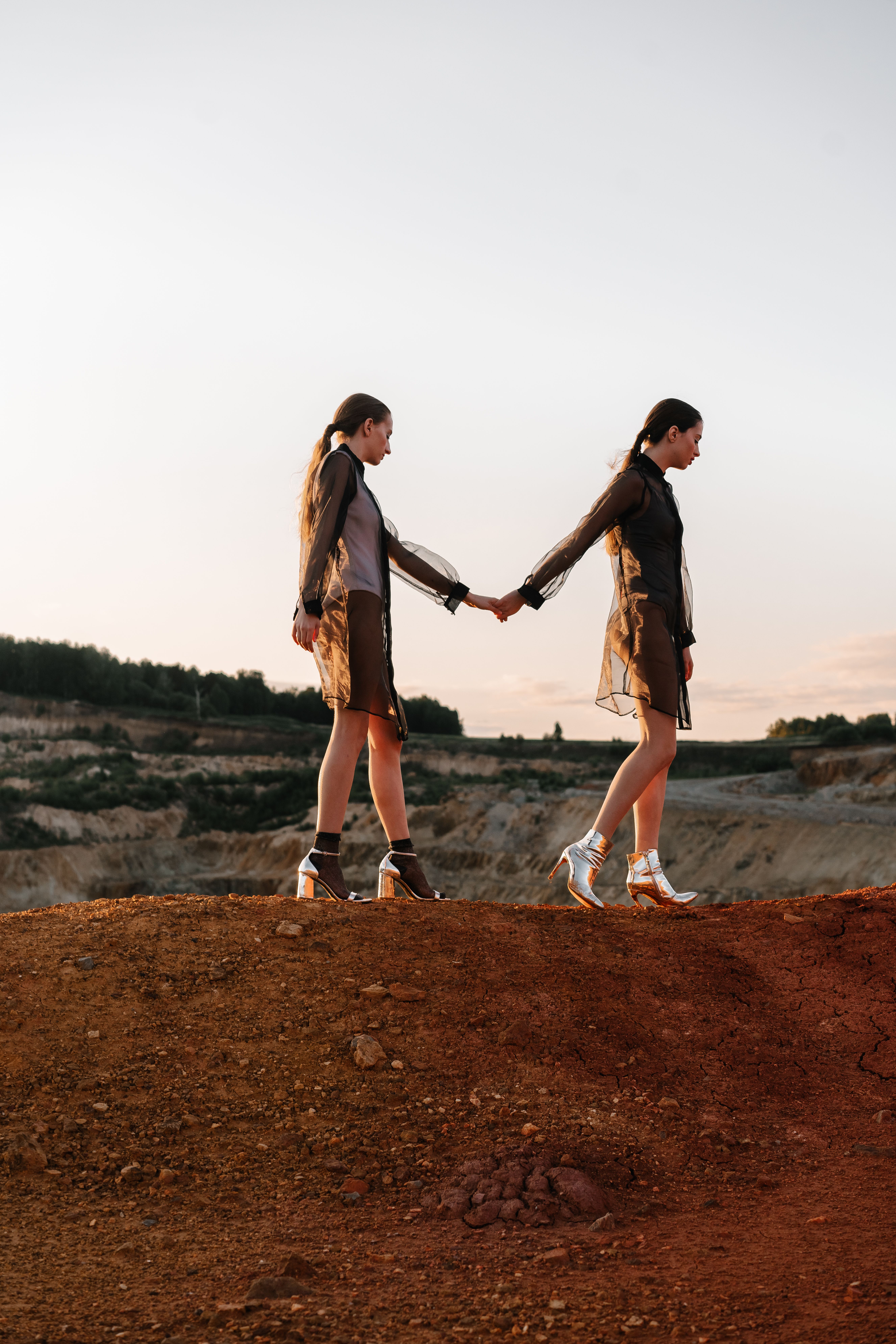 Two Women Holding Hands While Walking on Red Sand · Free Stock Photo