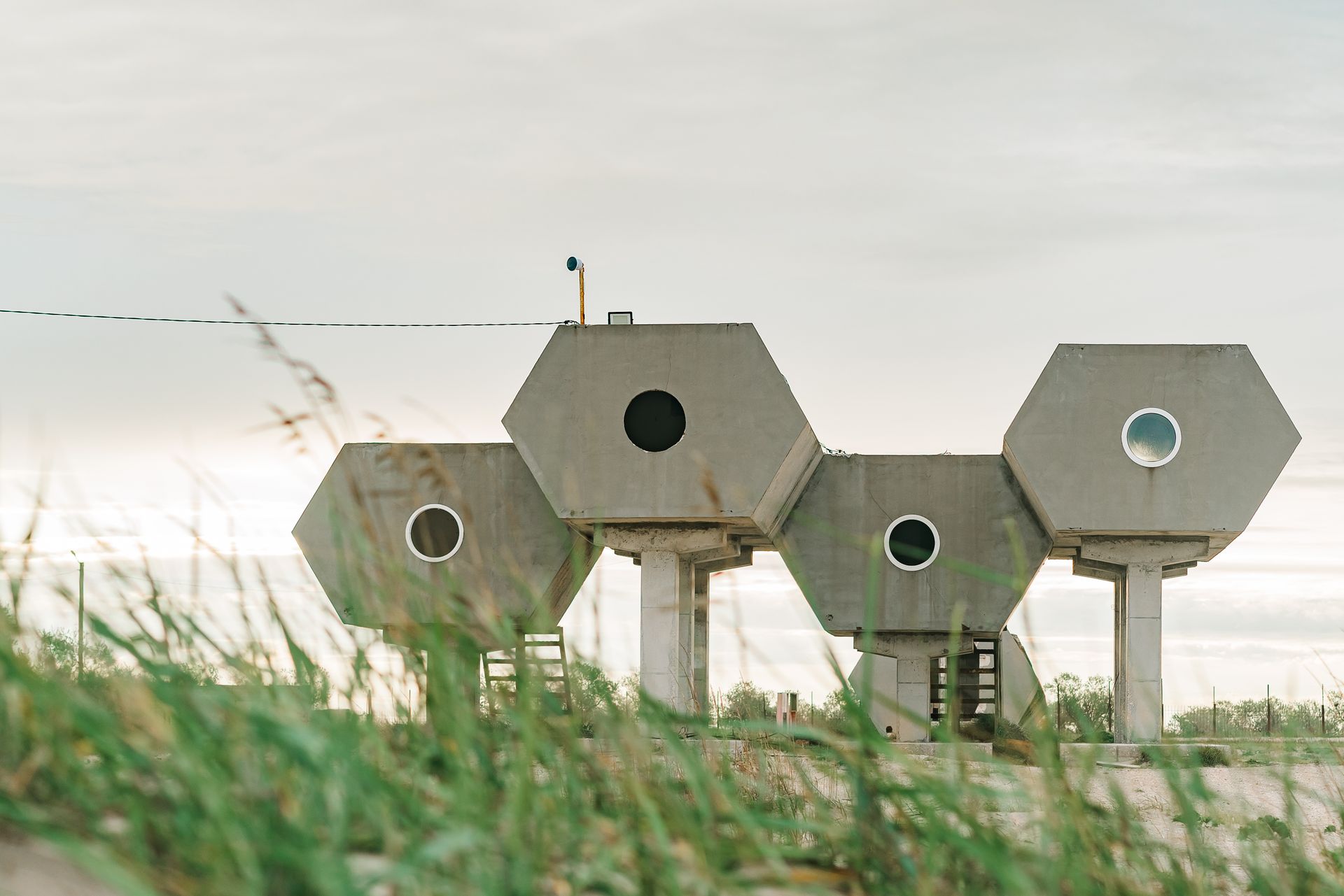 Futuristic hexagonal structures standing in an open field against a white sky.