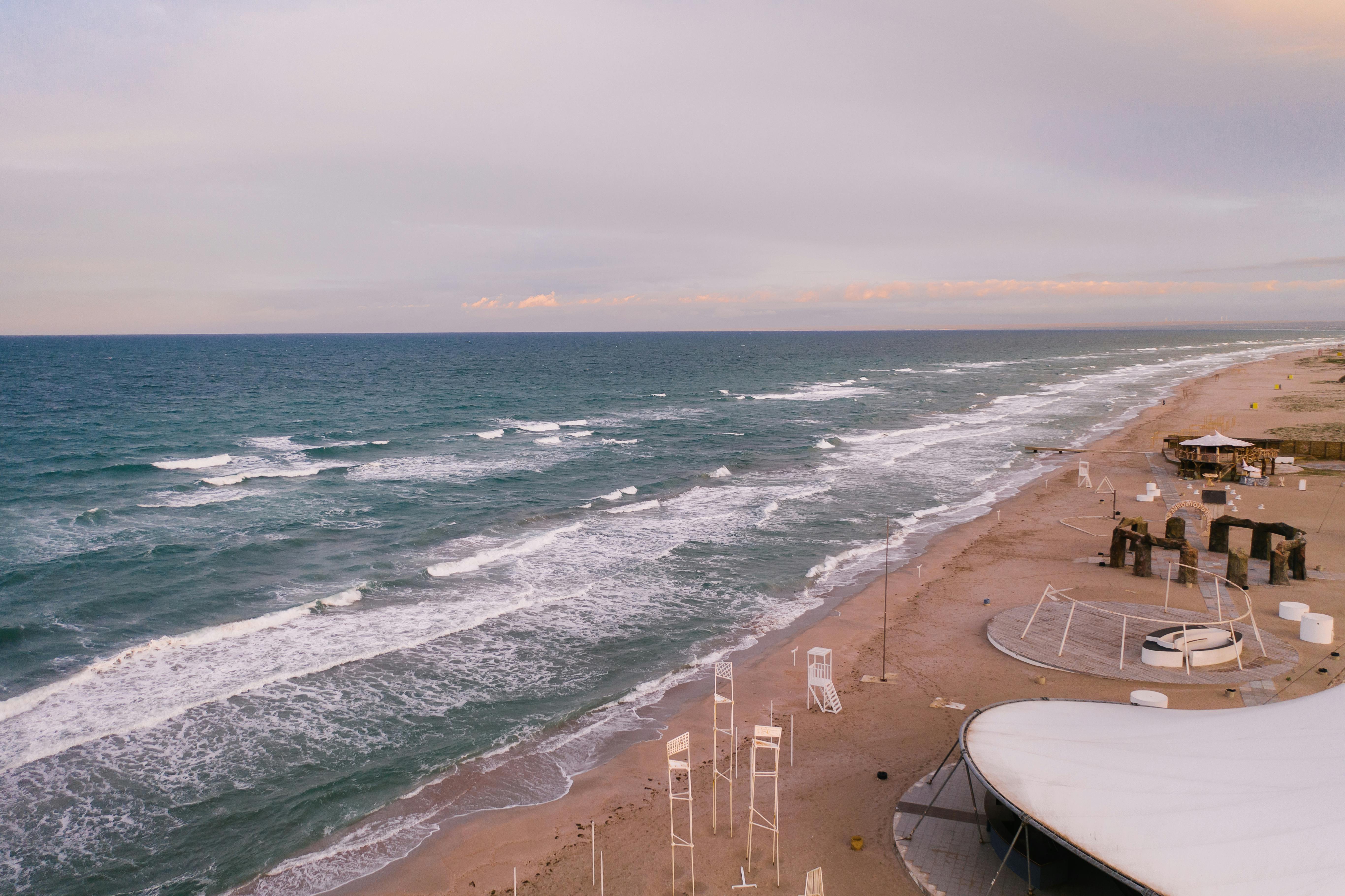 A serene aerial view of Popivka beach with gentle waves and a pastel sunset. Perfect for travel inspiration.