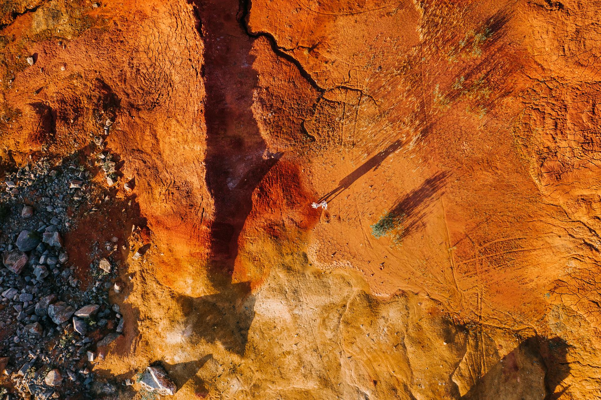 Top-down aerial shot of a vibrant orange and brown rocky landscape in Russia's Kemerovskaya oblast'.