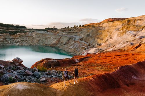Free Two women exploring the vibrant landscape of Guryevsky quarry lake at sunset. Stock Photo