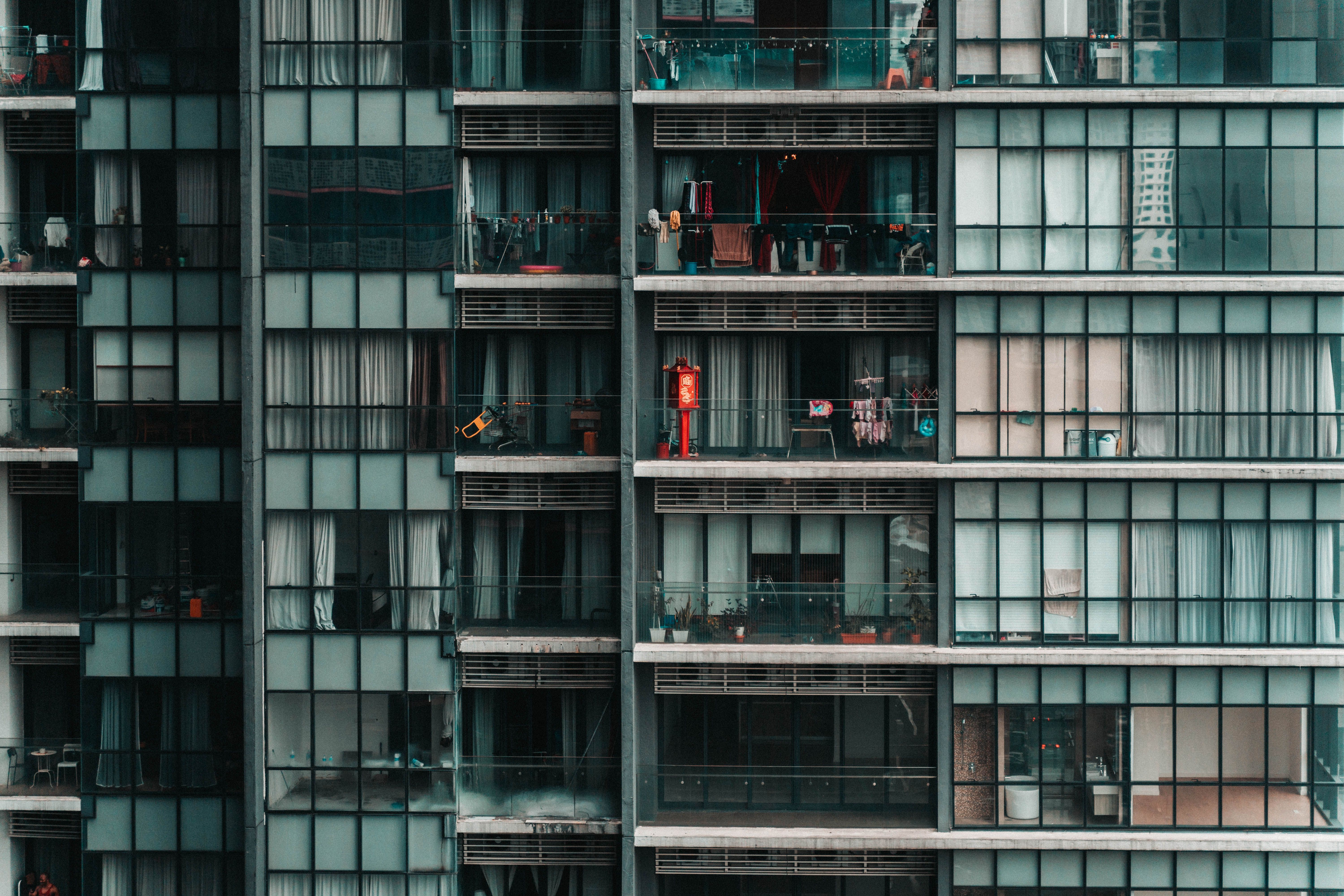Facade of a modern apartment building with stacked balconies — units share continuous plumbing and service risers