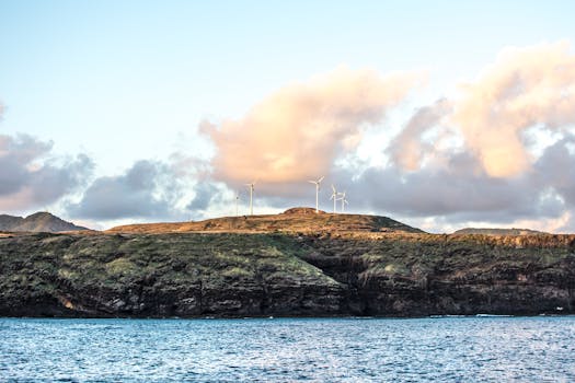Serene ocean view with cliffs and wind turbines in Açores under a vibrant sky.