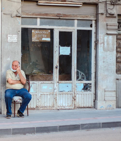 Citizen resting on chair between abandoned building and road