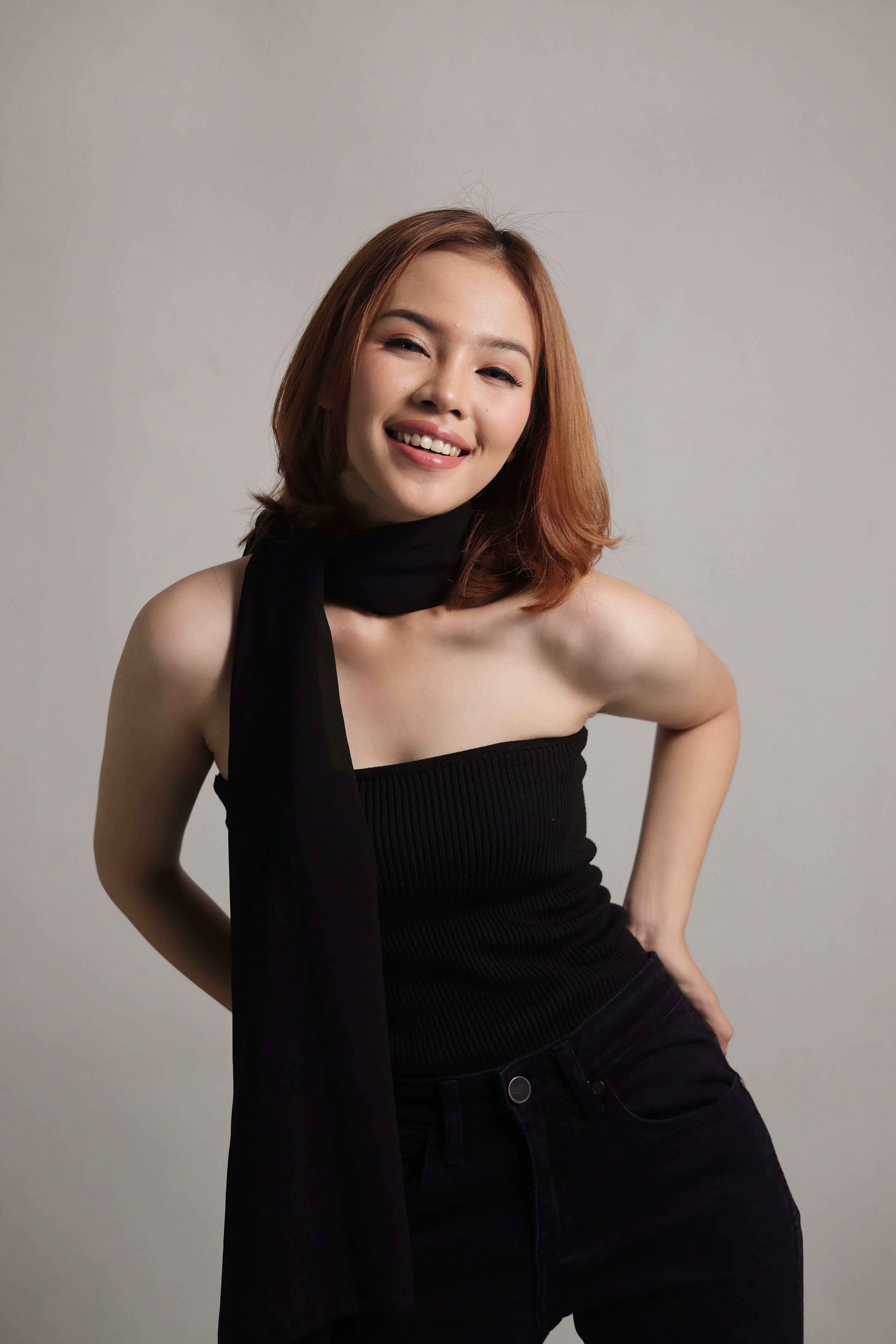 Asian woman in a fashionable black outfit posing with a smile.