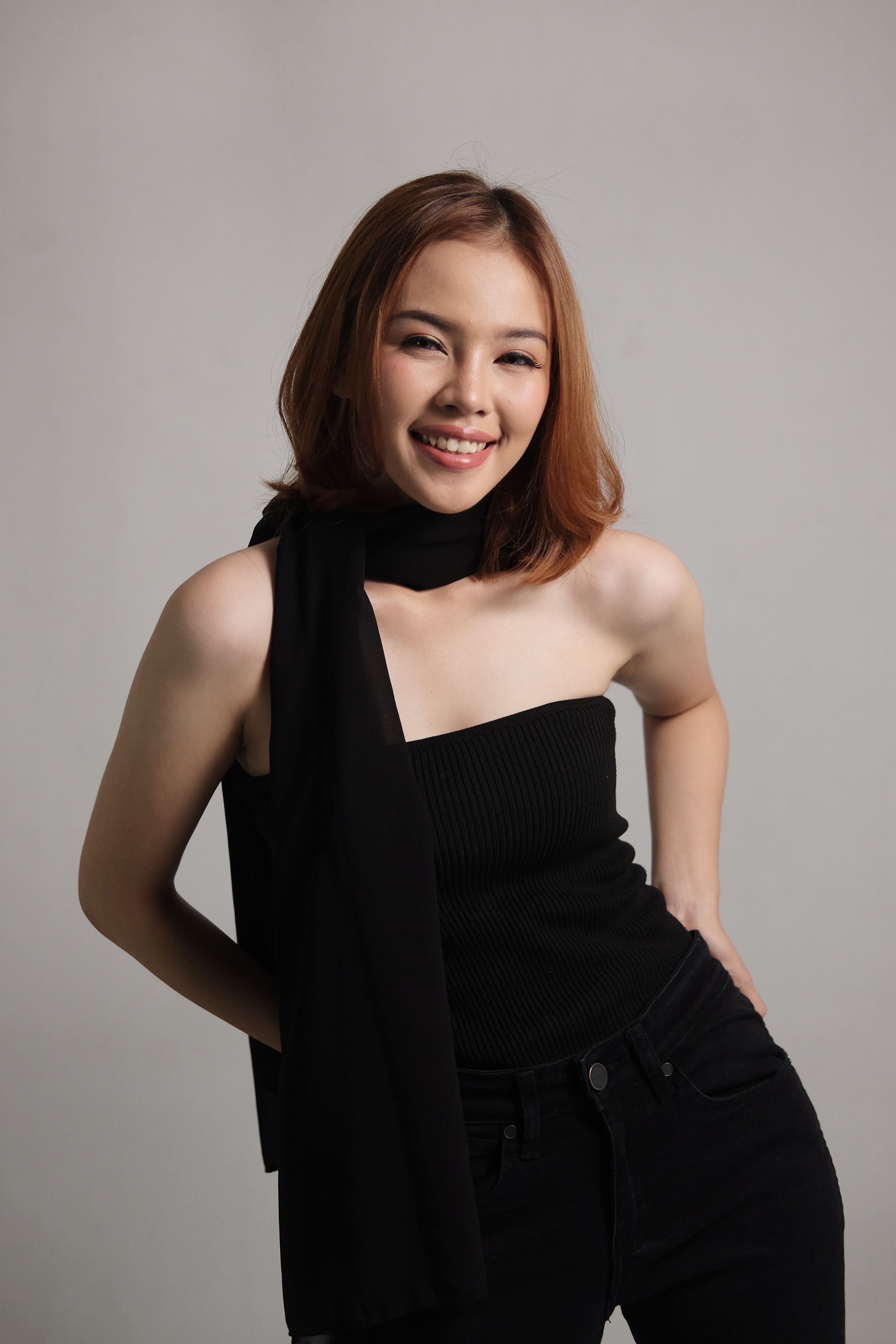 Studio portrait of a smiling woman posing against a gray background.