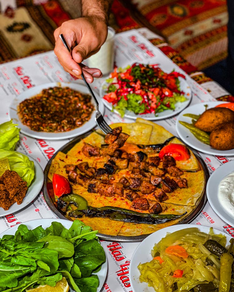 Person Hand Tasting Traditional Food From Table