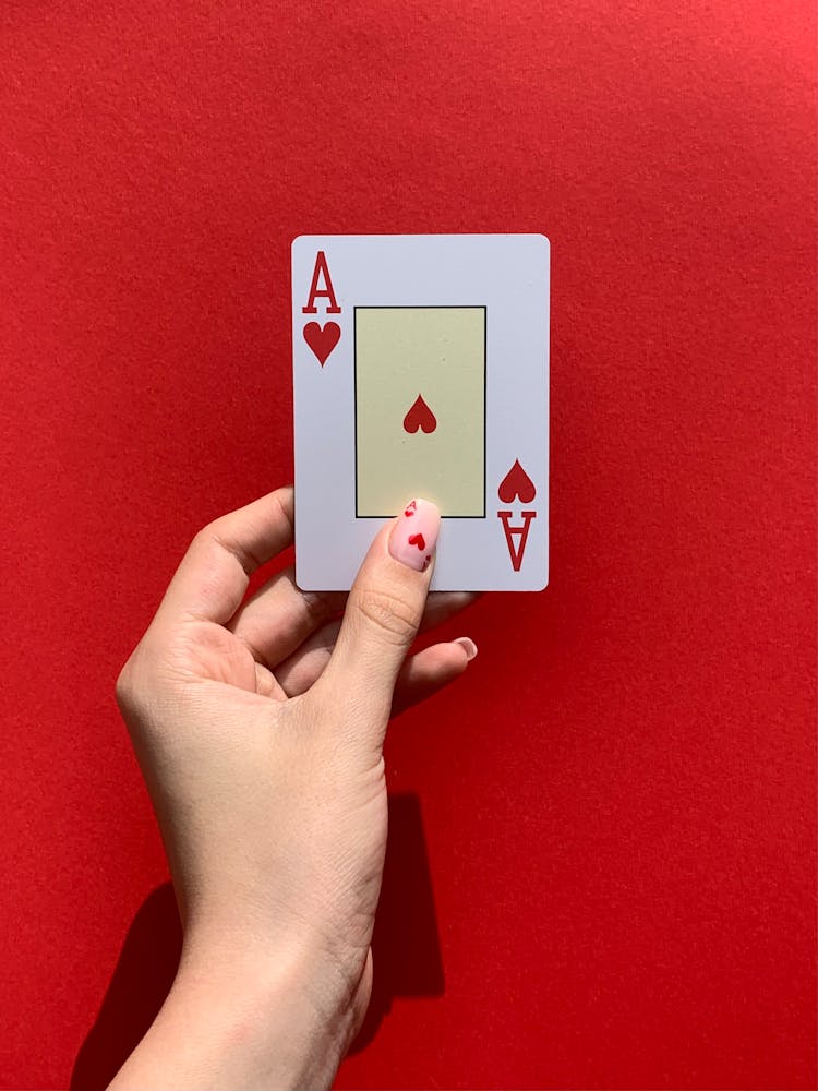 A Person Holding An Ace Of Hearts Card