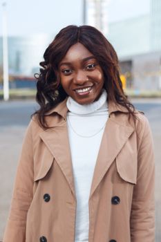 African American woman smiling in brown coat and turtleneck outdoors in Nanjing.
