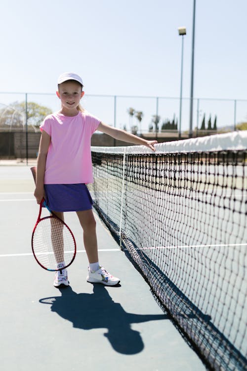 Free Girl Wearing Sportswear Standing by the Tennis Net Stock Photo