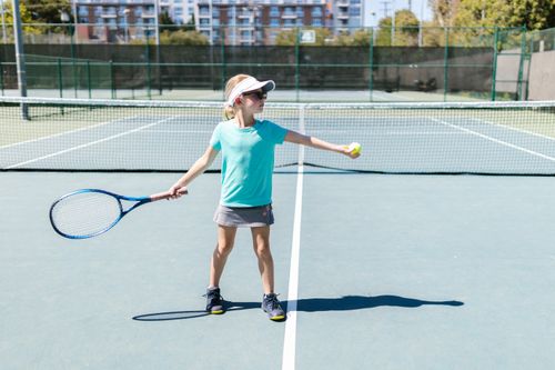 Free A young girl playing tennis on an outdoor court during a sunny day. Stock Photo
