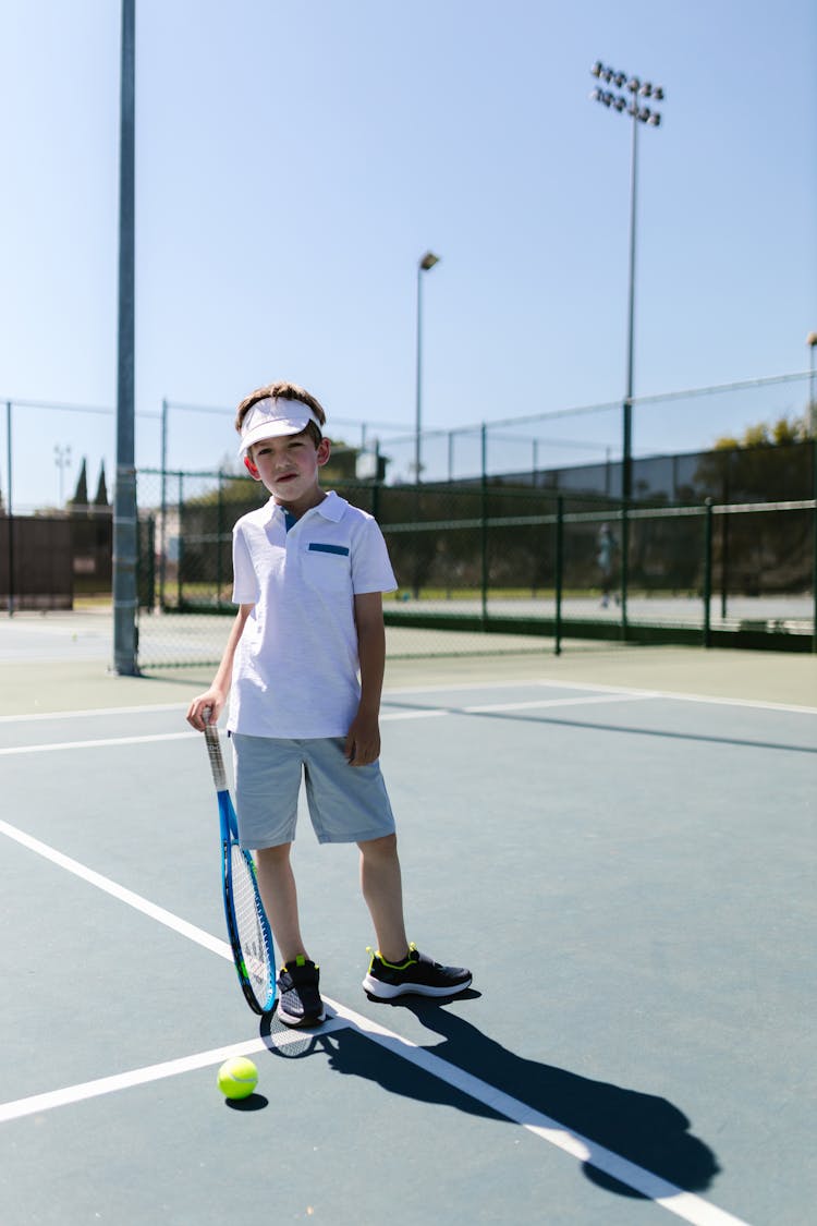 Boy In Sportswear Standing On The Tennis Court