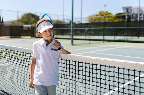 Free Boy Wearing Sportswear Standing by the Tennis Net Stock Photo