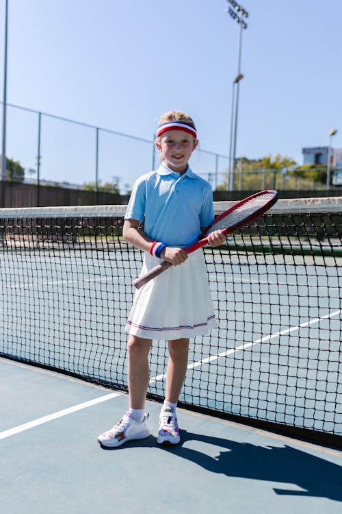 Free Girl Wearing Sportswear Standing by the Tennis Net Stock Photo