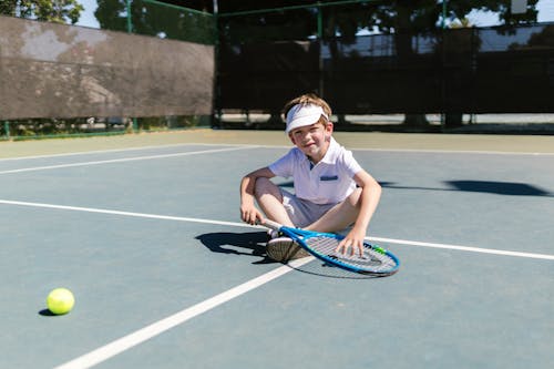Boy Smiling while Sitting on the Tennis Court