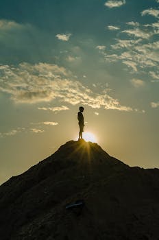 A silhouette of a person standing on a peak during a stunning sunset, capturing the essence of adventure and awe.