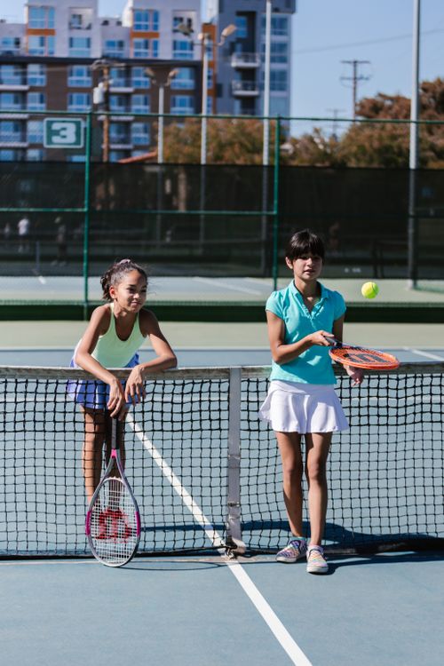 Free Two girls in sportswear play tennis on an outdoor court, enjoying the game. Stock Photo