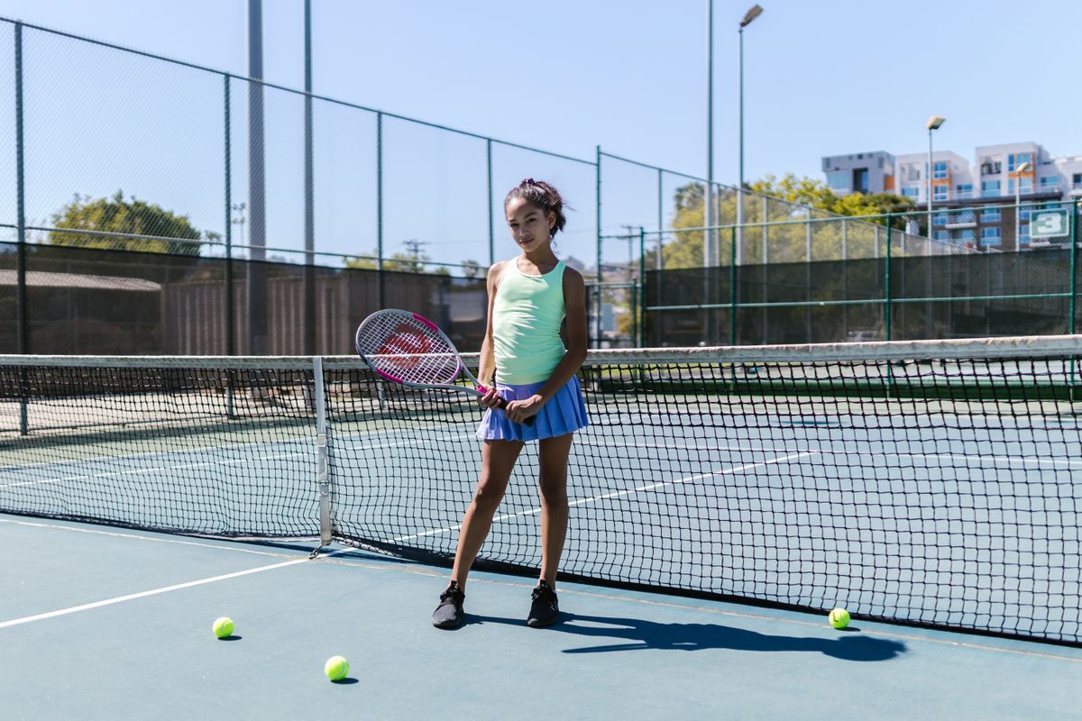 Player in sportswear standing by the tennis net on a sunny day