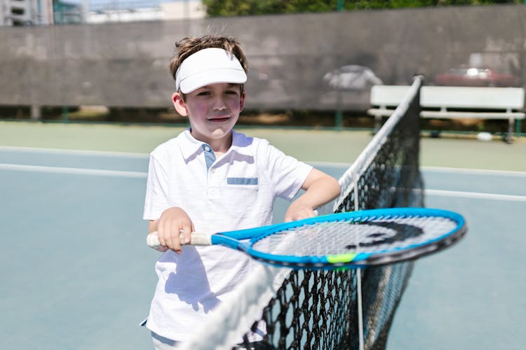 Close-Up View Of A Boy Wearing Sportswear Standing By The Tennis Net