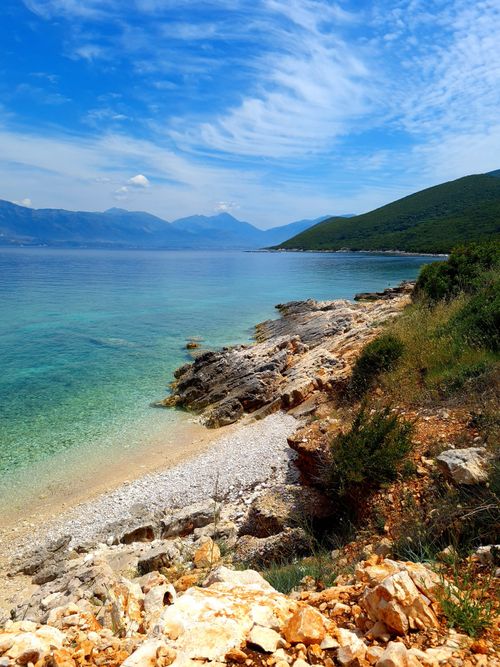 Free Beautiful rocky coastline with clear blue waters and verdant hills under a bright summer sky. Stock Photo