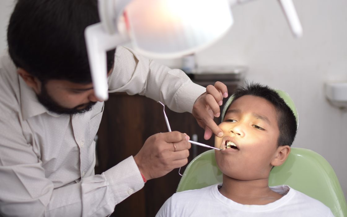 A dentist checks a child's teeth in a well-lit dental clinic, focusing on oral care.