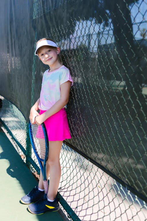 Girl Smiling while Standing by the Chain-Link Fence