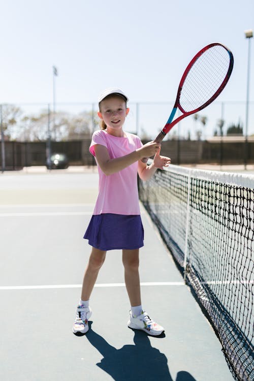 Girl in white sportswear stands on the tennis court near the net looking  away Stock Photo - Alamy