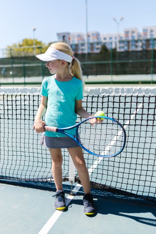 Free A young girl in sportswear holding a tennis racket and ball on an outdoor court. Stock Photo