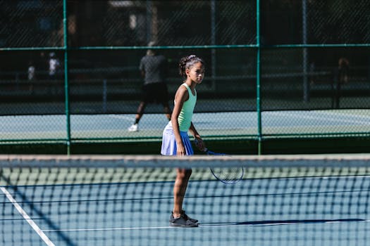 Young girl playing tennis on an outdoor court, showcasing active sports lifestyle.