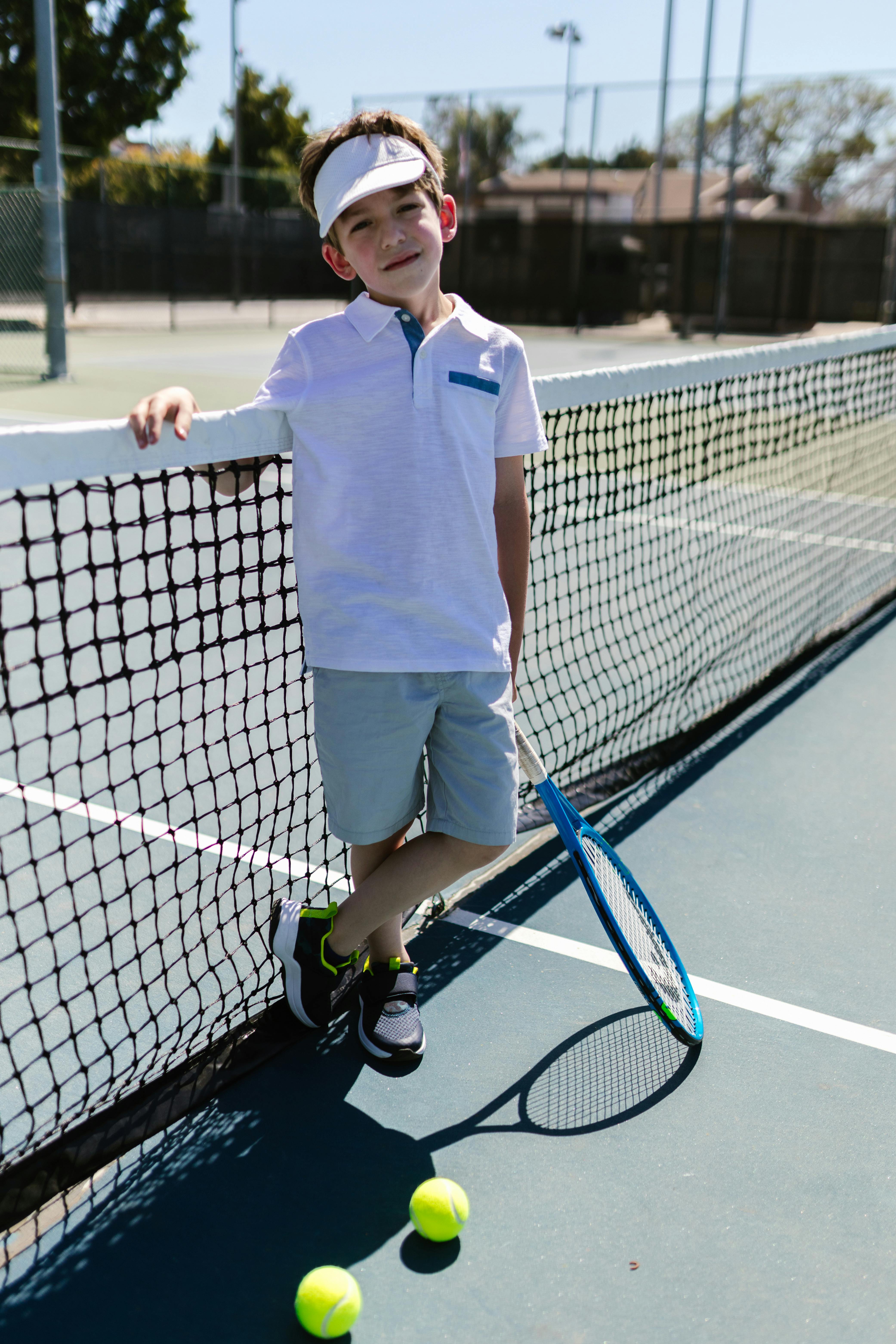 boy wearing sportswear standing by the tennis net