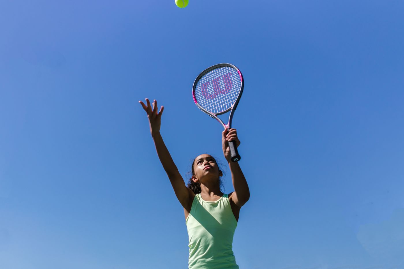 Player tossing the ball for a serve at sunset