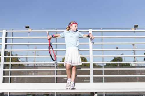 Girl in Sportswear Leaning on a Metal Fence