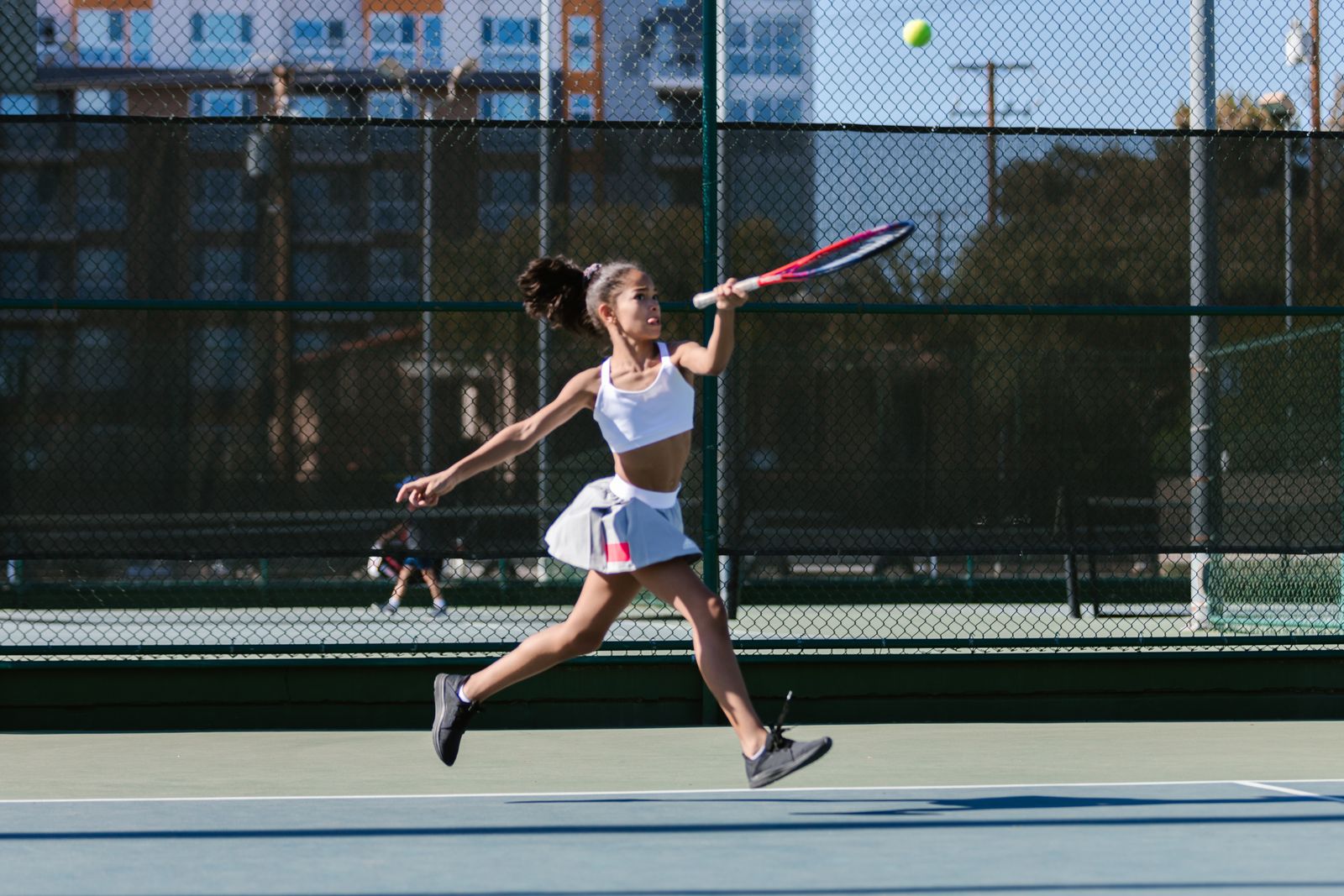 Tennis player extending the arm on a bright outdoor court
