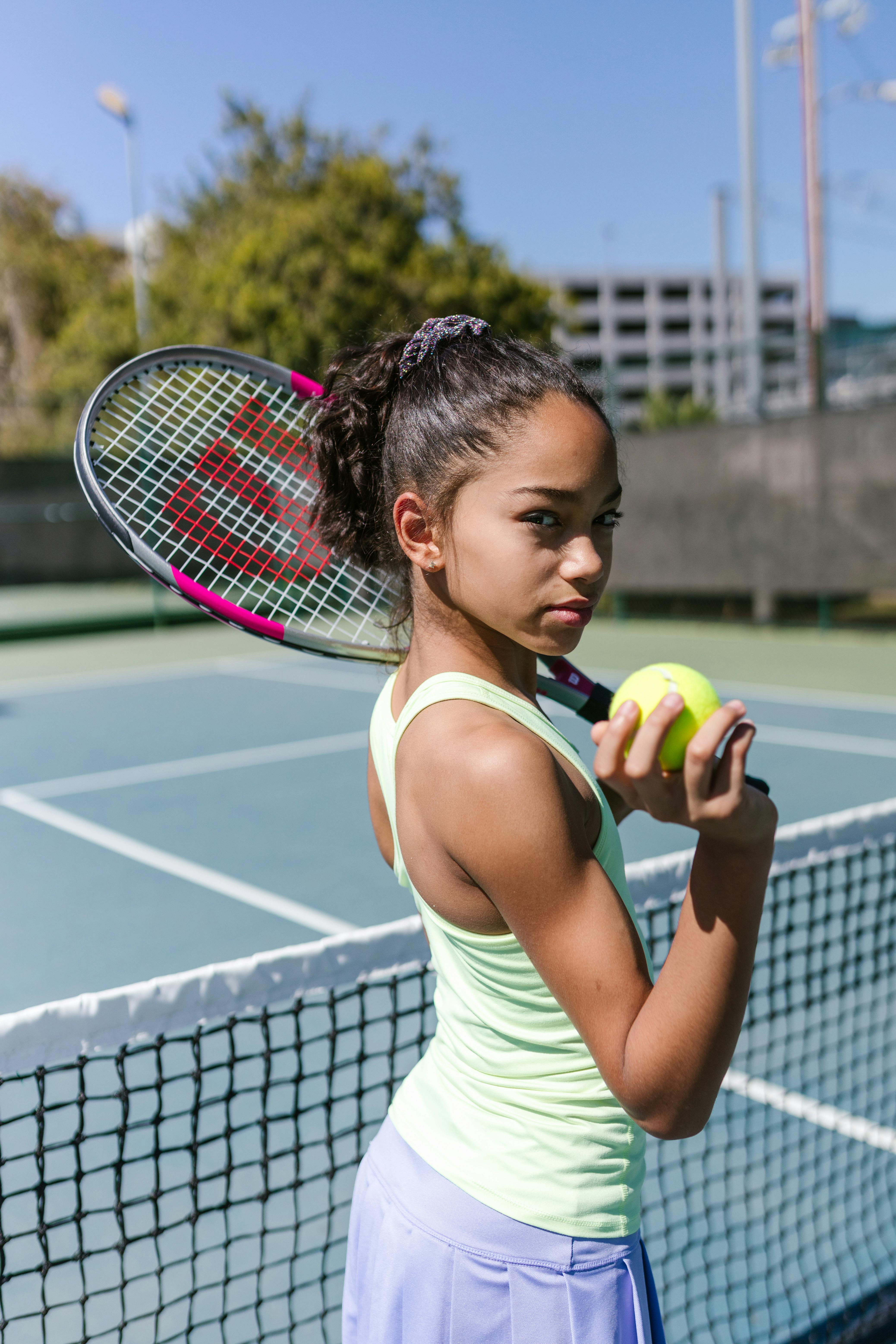 girl holding a tennis racket and tennis ball