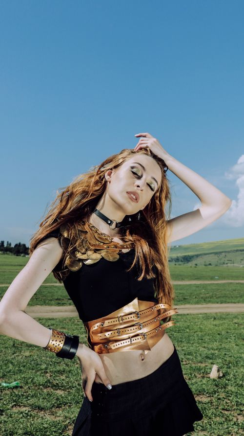 Free Stylish woman posing in a field with vibrant accessories and a striking outfit. Stock Photo
