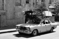 A Person Driving a Shabby Car Carrying Metal Scraps