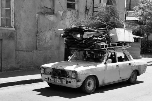 Old car with rooftop load on a sunny street in Tbilisi, Georgia.