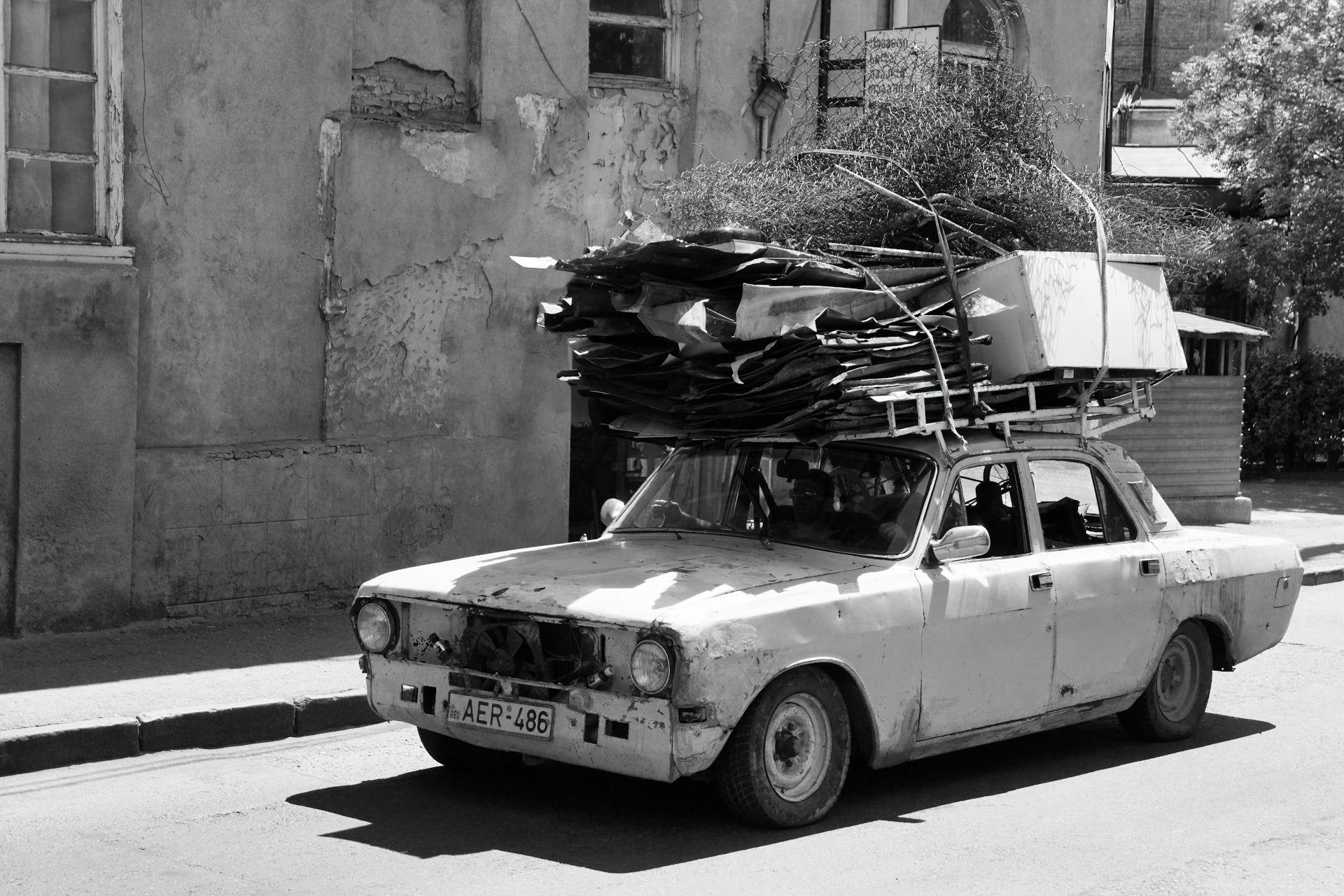 A Person Driving a Shabby Car Carrying Metal Scraps